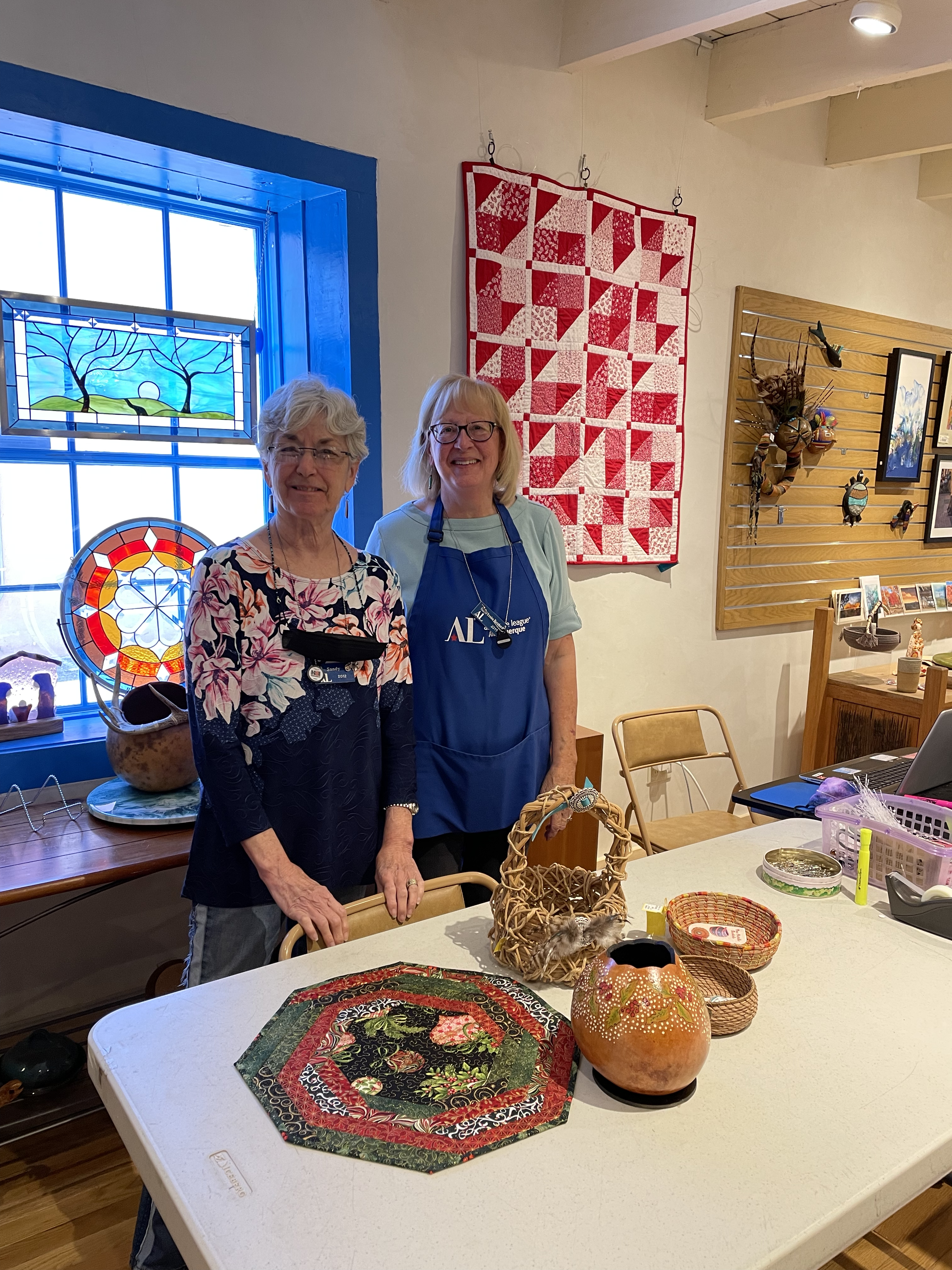 Two women stand with items for sale